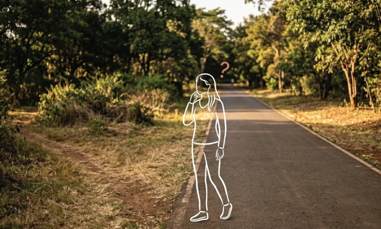 A Nairobi park path splitting into a maintained paved route and a worn overgrown shortcut through dry grass, afternoon light across both options